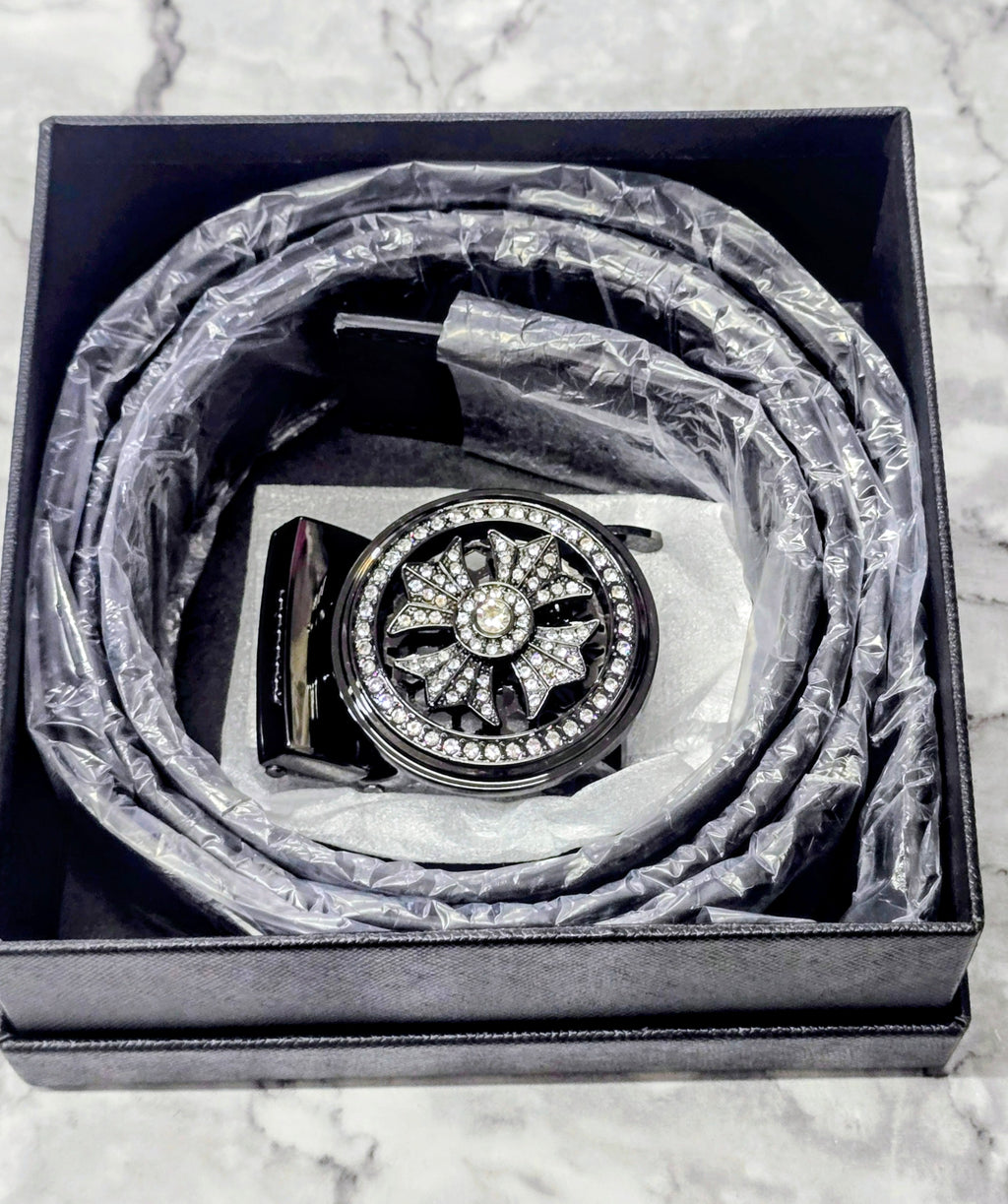 Men's black belt with ornate round rhinestone buckle, coiled in box