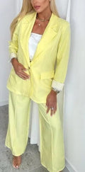 Women's yellow suit with blazer and wide-leg trousers, striped cuffs visible