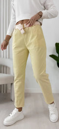 Corrux yellow trousers with belt loops, secured with a light belt at the waist.