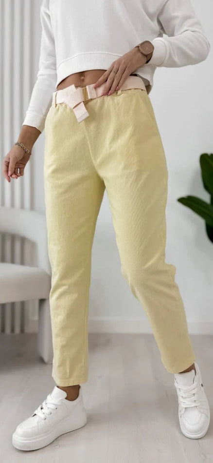 Corrux yellow trousers with belt loops, secured with a light belt at the waist.