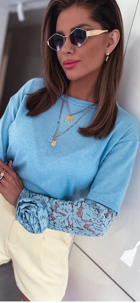 Light blue women's blouse with lace cuffs and small rose applique at chest