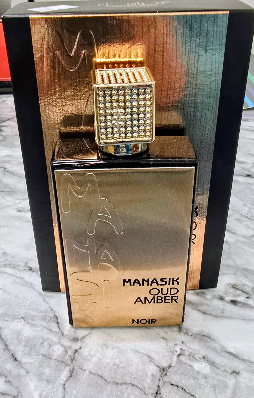 Perfume bottle set in box with cap; MANASIK OUD AMBER NOIR label on amber base