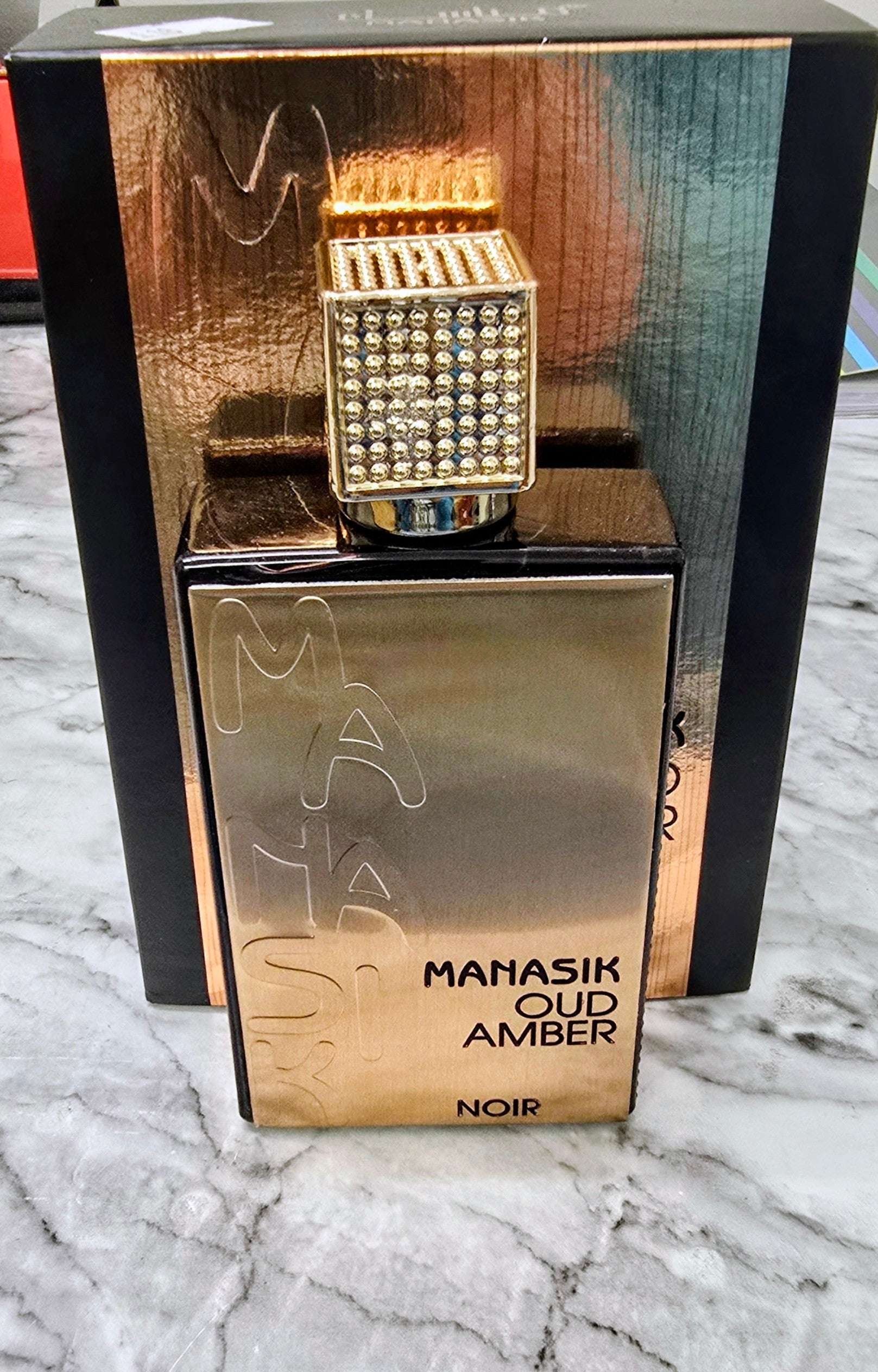 Perfume bottle set in box with cap; MANASIK OUD AMBER NOIR label on amber base